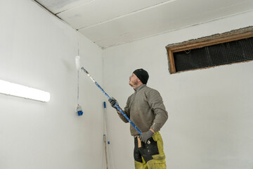 Dedicated Craftsman in Work Clothes Adds Final Touches to White Garage Painting.