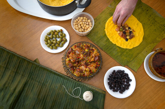 Hechura de hallacas andinas venezolanas. Se preparan con masa de harina de maíz, guiso crudo de carne de res, pollo y cerdo, aceitunas o alcaparras, pasas y garbanzos. Se envuelven en hojas de plátano