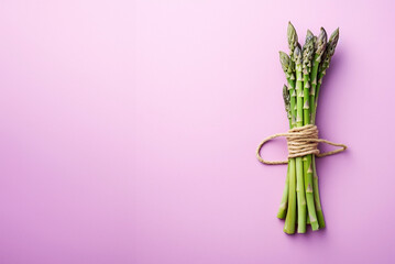 Bunch of asparagus on purple background with copy space