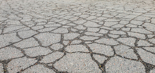 Cracked bitumen on the road. Cracks in the asphalt on the highway. The sidewalk and roadway part for transport needs repair. Old road with cracked damaged destroyed worn broken broken dirty asphalt