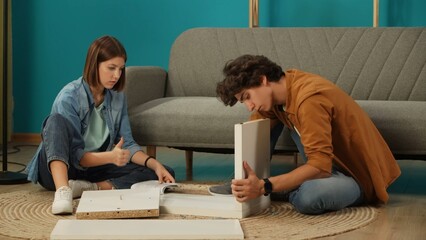 Close up shot of apartment living room. Man assembling new furniture puts details together, woman...