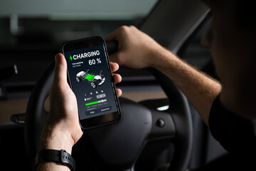 Electric car driver checks battery charging status, range and charging limit on app screen in the car. Smart technology device show EV car recharging data of electric storage in car battery innards. - obrazy, fototapety, plakaty