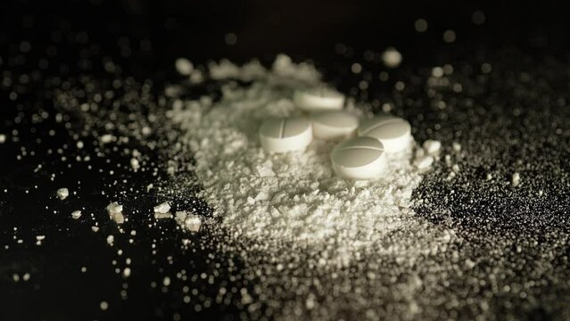 Shallow depth of view at white crystalline powder made of crushed oxycodone prescription medications pills. Opioid powdered drugs. Extreme macro close up of hand made Illegal narcotic substance.