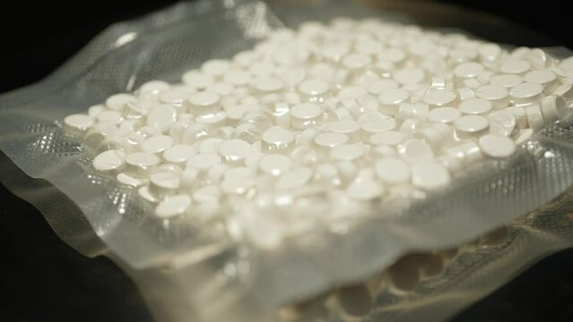 Illegal drugs in the vacuum bag, packaged for transportation by drugs trafficking. Powder drugs pressed in pills shape. Bags of Oxy, Meth, Fentanyl and other synthetic opioid drugs.