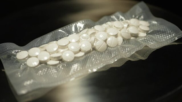 Powder drugs pressed in pills shape and packaged in to vacuum bags for transportation. Stash of Oxy, Meth, Fentanyl or synthetic opioid drugs, seized by police or security, illegal drugs trafficking.