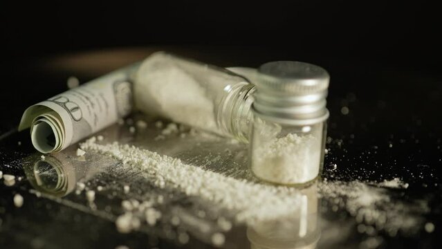 Heroin or crushed oxycodone placed in a container. Powdered illegal drugs stored in a glass vial, indicating substance abuse. Ongoing crisis involving opioids and fentanyl.