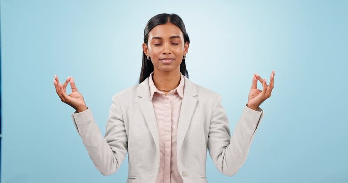 Calm, meditation and business woman in studio for zen, positive and peaceful mindfulness. Yoga, balance and young Indian female person breathing to relax for chakra energy isolated by blue background
