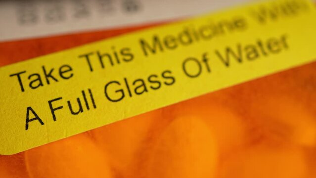 Prescription bottle with warning stickers saying, Take this medicine with glass of water. Opioids medications are effective in managing moderate to severe pain that persists over an extended period.