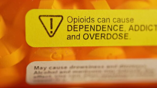 Prescription bottle with warning stickers saying, Opioids can cause dependence, addiction and overdose. Opioids are commonly prescribed to alleviate various types of chronic pain.
