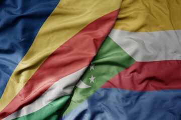 big waving national colorful flag of seychelles and national flag of comoros .