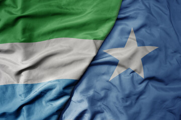 big waving national colorful flag of sierra leone and national flag of somalia .
