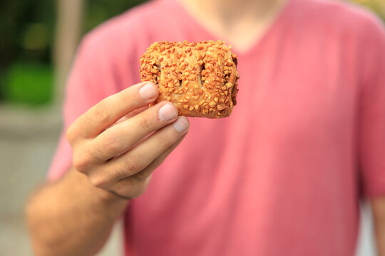 A guy's hand holds sweet pastry with jam, snack and fast food concept. Selective focus on hands with blurred background