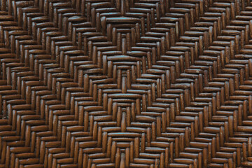 A close up of a woven wood surface texture and pattern. a handmade woodwork furniture in brown color, antique and old with high details. Diagonal lines, similar and seamless symmetrical pattern.