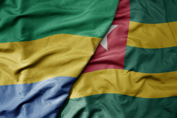 big waving national colorful flag of togo and national flag of gabon .