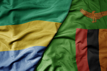 big waving national colorful flag of zambia and national flag of gabon .