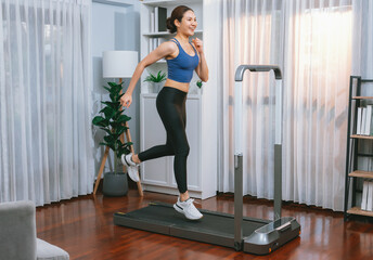 Energetic and strong athletic asian woman running running machine at home. Pursuit of fit physique...