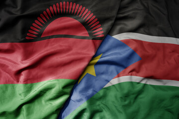 big waving national colorful flag of south sudan and national flag of malawi .