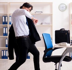 Young male employee in the office in time management concept