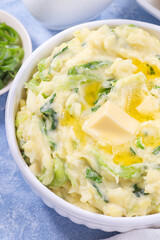 Traditional Irish dish Colcannon or mashed potato with green cabbage and butter, vertical closeup