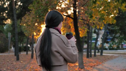Woman sipping coffee as waiting for business meeting in town park in autumn