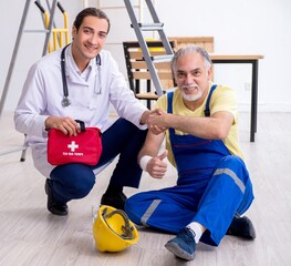 Young male doctor and old contractor in first aid concept