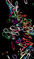 Fashion Safety Pin brooch pour fall down, explosion in air. Many safety pin big size colorful splash fly in group floating. Black background isolated freeze motion