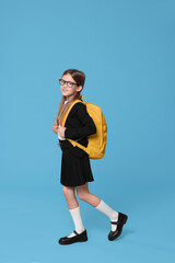 Fototapeta na wymiar Happy schoolgirl with backpack on light blue background