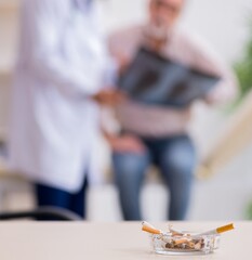 Young male doctor and old patient in antismoking concept