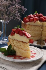 Piece of tasty cake with fresh strawberries and mint on blue wooden table
