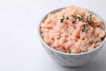 Fresh raw minced meat and thyme in bowl on light grey table, closeup. Space for text