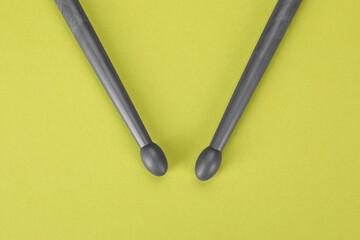 Two gray drum sticks on light green background, top view