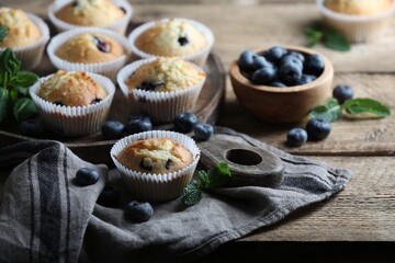 Delicious sweet muffins with blueberries and mint on wooden table