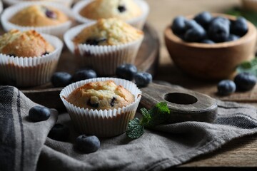 Delicious sweet muffins with blueberries and mint on wooden table, closeup