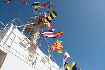 honorary flag dressings on the main mast of a cargo ship with international code of signal flags in...