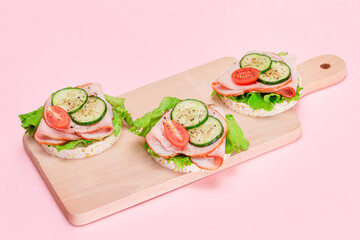 Light Breakfast. Quick and Healthy Sandwiches. Rice Cakes with Ham, Tomato, Fresh Cucumber and Green Salad on Wooden Cutting Board