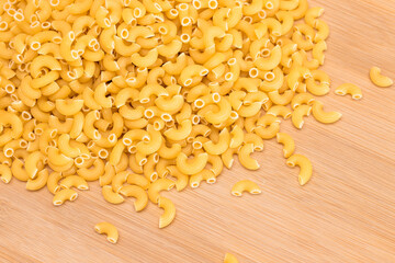 A Heap of Uncooked Chifferi Rigati Pasta on Wooden Kitchen Board. Fat and Unhealthy Food. Classic Dry Macaroni. Italian Culture and Cuisine. Raw Pasta