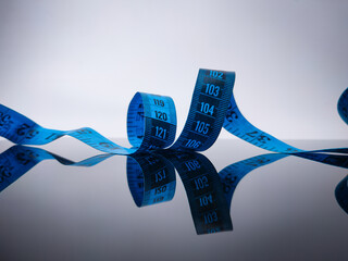 Closeup blue measuring tape with reflection on a black acrylic board