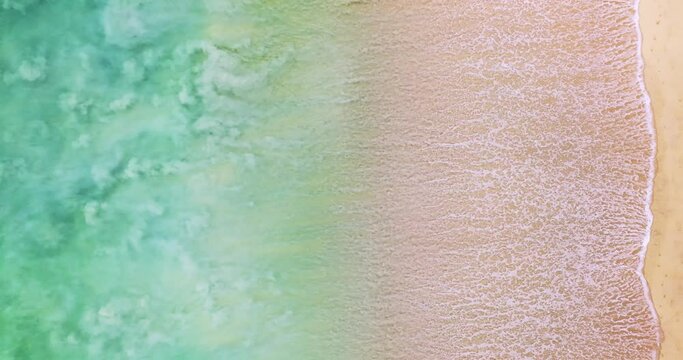 Aerial view of sea crashing waves White foaming waves on beach sand,Top view beach sea surface texture background,Amazing colorful beach sea wonderful sand background