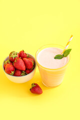Glass of tasty strawberry smoothie on yellow background