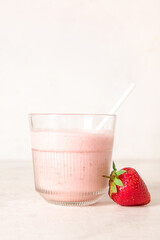 Glass of tasty strawberry smoothie on light background