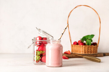 Mason jar of tasty strawberry smoothie on light background