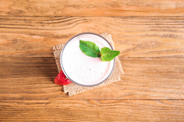 Glass of tasty strawberry smoothie on wooden background