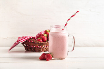 Mason jar of tasty strawberry smoothie on table