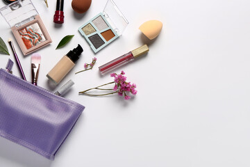 Stylish purple cosmetic bag with makeup products and beautiful flowers on white background - obrazy, fototapety, plakaty