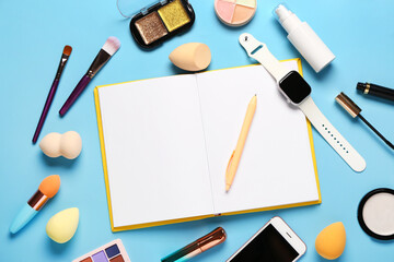 Composition with makeup cosmetics, modern mobile phone, smartwatch and notebook on blue background