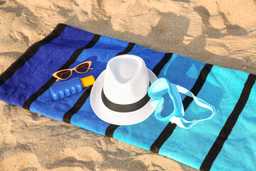 Colorful towel with beach accessories on sand