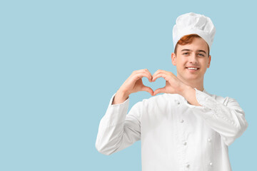 Male confectioner in uniform showing heart gesture on blue background