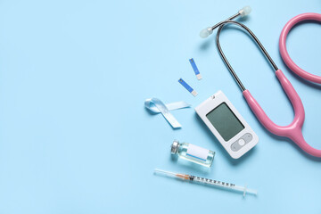 Awareness ribbon with insulin, glucometer and stethoscope on blue background. Diabetes concept