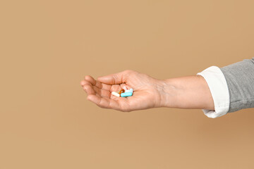 Female hand with pills on brown background