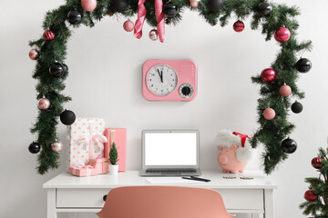 Workplace with blank laptop, presents and Christmas decor in office